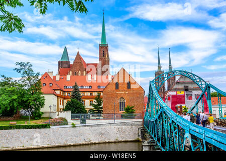 Wroclaw, Polen - 21. Juni 2019: dominsel Brücke, die zum Ostrow Tumski Bezirk. Glockentürme von der Kirche des Heiligen Kreuzes und der Kathedrale von S Stockfoto