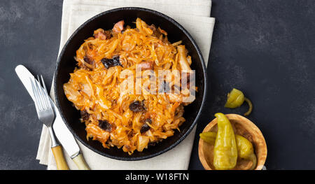 Traditionelle Gerichte der polnischen Küche - Bigos aus frischem Kohl, Fleisch und Pflaumen. Ansicht von oben. Der dunkle Hintergrund. Stockfoto