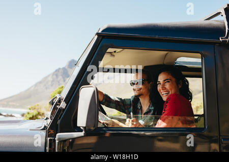 Glückliches junges Paar auf einer Fahrt in einem Auto. Lächelnde junge Frau mit ihrem Freund fahren Auto. Stockfoto