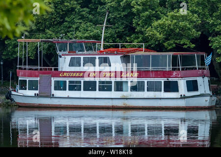 IOANNINA, Griechenland - 6 Juni, 2019 - kleine alte weiße und rote touristische Kreuzfahrt Fährschiff mit zwei Decks Liegeplatz am See Pamvotida in der Nähe der wunderschönen kleinen griechischen Stadt aufgegeben. Wasser Reflexionen. Stockfoto