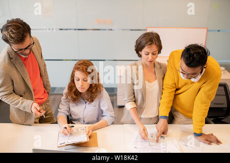 Gruppe von nachdenklich konzentrierte junge multi-ethnischen Business Analysten lesen Papiere und Prüfung von Informationen zusammen im Büro Stockfoto