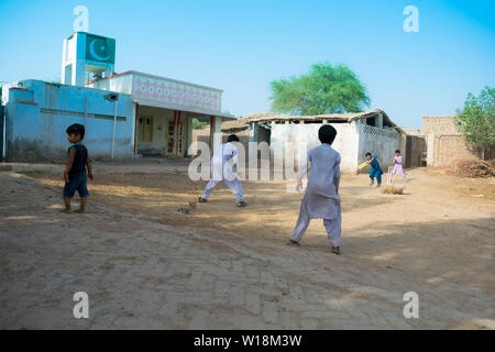 Rahimyar Khan, Punjab, Pakistan - Juli 1,2019: Einige lokalen jungen Kricket spielen in einem Dorf, batsman spielt einen Schuß, Staub fliegen. Stockfoto
