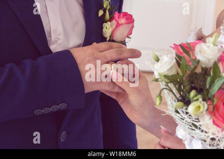 Hochzeit der Braut und des Bräutigams. Die Braut trägt einen Ehering am Finger des Bräutigams. Stockfoto