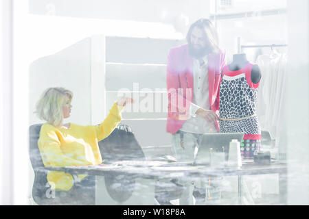 Ansicht von hinter Glas. Modedesigner diskutieren neue Designs für Kleidung. Stockfoto