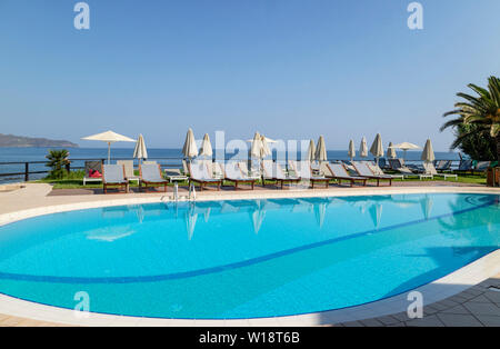 Kreta, Griechenland. Juni 2019. Sonnenliegen am Pool mit Blick auf den Pool auf die Bucht von Chania Norden von Kreta. Stockfoto