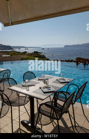 Kreta, Griechenland. Juni 2019. Restaurant am Pool Tisch und Stühlen mit Blick auf die Bucht von Chania Norden von Kreta. Stockfoto