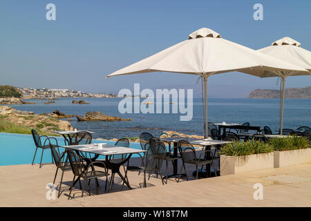 Kreta, Griechenland. Juni 2019. Restaurant am Pool Tisch und Stühlen mit Blick auf die Bucht von Chania Norden von Kreta. Stockfoto