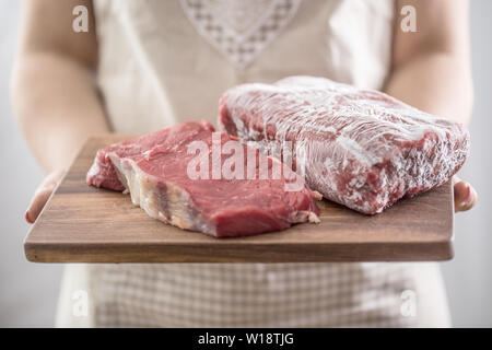 Frau Koch Holding Holzbrett von Roh- und gefrorenem Rindfleisch Stockfoto