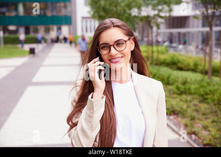 Nahaufnahme mit einem Handy der Geschäftsfrau und im Gespräch mit jemand beim Gehen auf die Straße. Stockfoto