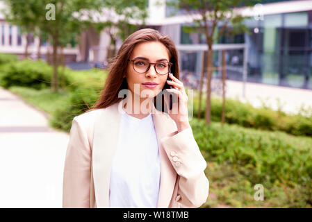 Nahaufnahme mit einem Handy der Geschäftsfrau und im Gespräch mit jemand beim Gehen auf die Straße. Stockfoto