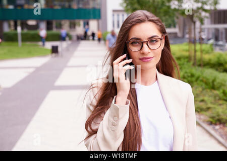 Nahaufnahme mit einem Handy der Geschäftsfrau und im Gespräch mit jemand beim Gehen auf die Straße. Stockfoto