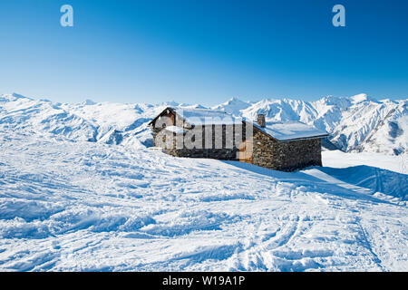 Panorama der schneebedeckten Berge in ein alpines Skigebiet mit Gebäude aus Stein auf entfernten Hang Stockfoto