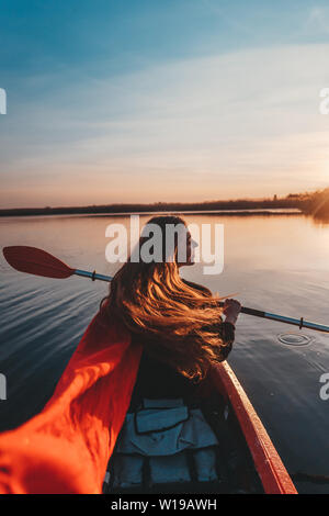 Rückansicht des Happy cute girl Holding Paddeln im Kajak auf dem Fluss Stockfoto