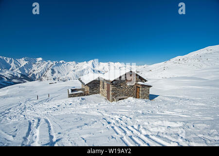 Panorama der schneebedeckten Berge in ein alpines Skigebiet mit Gebäude aus Stein auf entfernten Hang Stockfoto