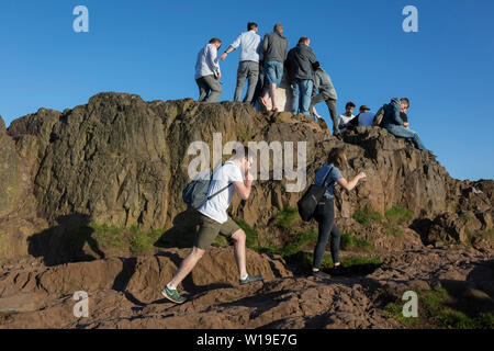 Im Sommer abends Sonnenschein, Wanderer besteigen die letzten Meter zum Gipfel des Arthur's Seat in Holyrood Park, die Stadt Edinburgh überblickt, am 26. Juni 2019 in Edinburgh, Schottland. Arthur's Seat ist ein erloschener Vulkan, der Hauptgipfel der Gruppe von Hügeln in Edinburgh, Schottland, welche Form die meisten Holyrood Park, von Robert Louis Stevenson als "ein Hügel für Größe beschrieben, ein Berg im Rahmen ihrer bold Design" betrachtet wird. Der Hügel erhebt sich über der Stadt auf einer Höhe von 250.5 m (822 ft), einen ausgezeichneten Panoramablick über die Stadt und darüber hinaus. Stockfoto