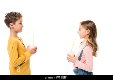 Seitenansicht von zwei Kindern Milchshakes halten und bei jeder anderen sich isoliert auf weißem Stockfoto