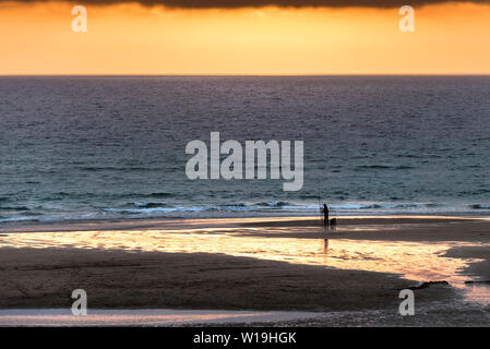 Ein einsamer Angler von einer atemberaubenden schönen goldenen Sonnenuntergang am Fistral Beach in Newquay in Cornwall. Stockfoto