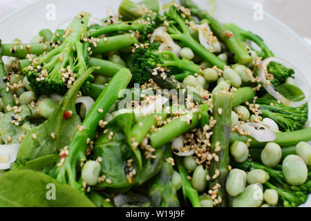 Lecker Frühjahr Salat von Baby, Brokkoli, Spargel, Bohnen, Spinat Blätter und Schalotte mit Sesam und Nigellasamen gekleidet Stockfoto