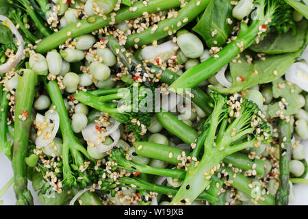 Frühjahr Salat von frischen grünen broccolini Stängel, Bohnen und grüne Bohnen, bestreut mit Sesam, Schalotte und nigellasamen Stockfoto