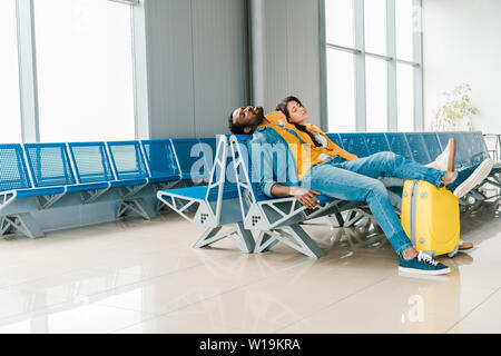 Müde afrikanische amerikanische Paar schlafen in der Abflughalle im Flughafen Stockfoto