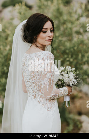 Braut holding Wedding Bouquet. Porträt der jungen Braut tragen elegante Lacey Brautkleid. Stockfoto