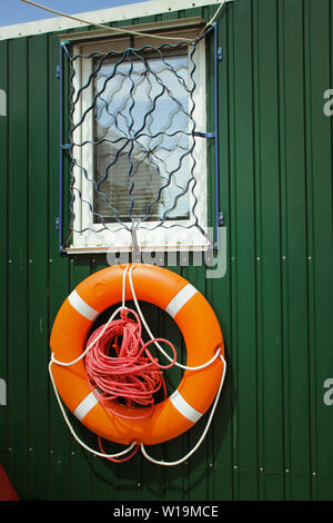 Eine orange Leben Boje auf ein grünes Holz- wand. Stockfoto