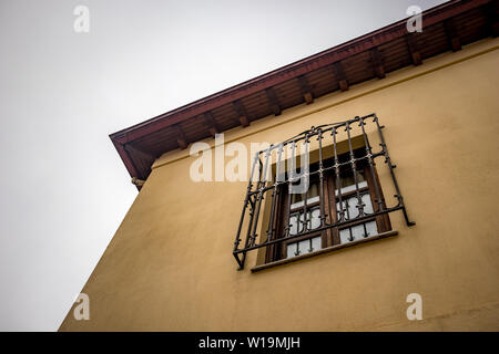 Schmiedeeisen abgedeckt Fenster auf Haus, Wohnhaus, Ioannina, Griechenland, Moody Frühling Morgen mit Nebel, Low Angle View Stockfoto