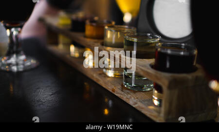 Bunte transparente Cocktails, eine Reihe von Aufnahmen in einer Zeile, sechs Portionen auf einem Stand aus Holz, Substrat. Getränk für das Menü, Restaurant, Bar, Cafe Stockfoto