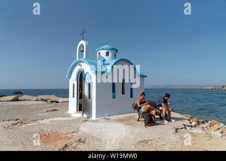 Kalamki Beach, Kreta, Griechenland. Juni 2019. Paar außerhalb des Blauen und Weißen fishermans sitzt Kapelle auf Kalamaki Hafen, Norden von Kreta. Stockfoto