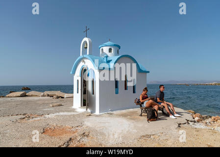 Kalamki Beach, Kreta, Griechenland. Juni 2019. Paar außerhalb des Blauen und Weißen fishermans sitzt Kapelle auf Kalamaki Hafen, Norden von Kreta. Stockfoto