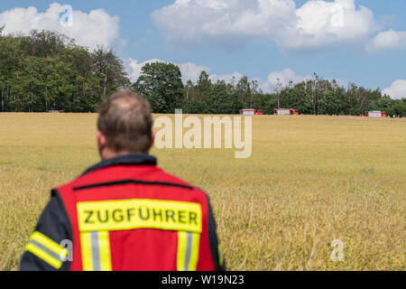 Dehmcurbrock, Deutschland. 01. Juli, 2019. Ein Feuerwehrmann steht auf einem Feld. Die Bundeswehr hat den Absturz eines Hubschraubers in Niedersachsen bestätigt. Der Eurocopter EC 135 Maschine wurde in einem Unfall etwa 30 Kilometer westlich von Hameln, ein Sprecher der Bundeswehr beteiligt die Deutsche Presse Agentur berichtet. Es hatte zwei Personen an Bord. Das Flugzeug gehört zu den International Helicopter Training Center in Bückeburg. Bild: Stefan Simonsen/dpa/Alamy leben Nachrichten Stockfoto