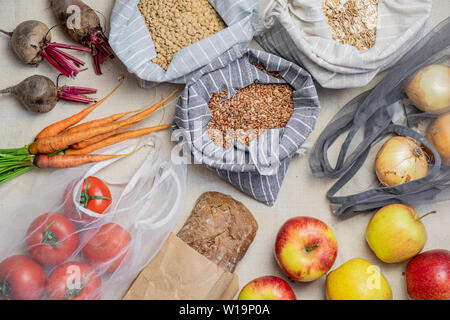 Lebensmittel in wiederverwendbarer Beutel auf natürliche Flachs oder Hanf Hintergrund, Ansicht von oben. Konzept der Null Abfall ethisches Einkaufen: raw vegan Essen einschließlich Obst, veget Stockfoto