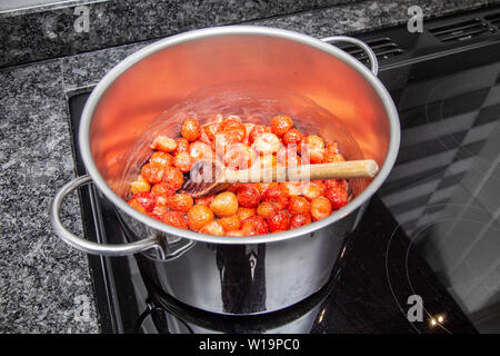 Heizung Erdbeeren uintil sie sind weich Erdbeermarmelade auf einem Induktionsherd, Edelstahl Pfanne. Stockfoto