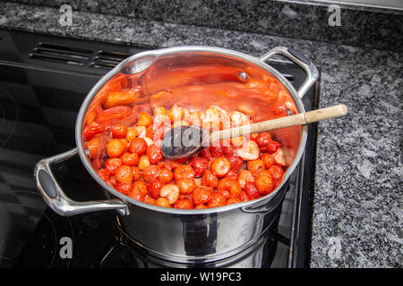 Heizung Erdbeeren uintil sie sind weich Erdbeermarmelade auf einem Induktionsherd, Edelstahl Pfanne. Stockfoto