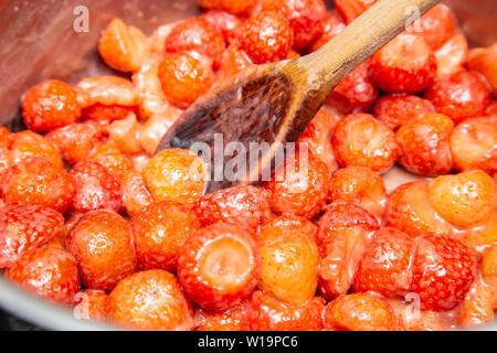 Heizung Erdbeeren, bis sie weich sind Erdbeermarmelade auf einem Induktionsherd, Edelstahl Pfanne. Stockfoto