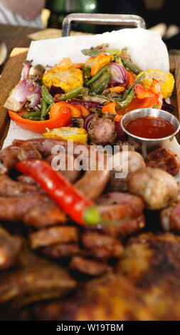Gemischte gegrillte Fleischplatte. Sortierte lecker Gegrilltes Fleisch mit Gemüse. Gemischte gegrilltes Fleisch mit Pfeffer Soße und Gemüse. Stockfoto