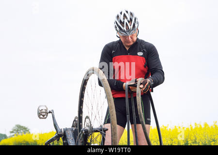 Ein Mann der Reparatur ein Fahrrad in ein Feld, eine Punktion eines Fahrrads Kamera auf dem Weg, der Region Kaliningrad, Russland, 19. Mai 2019 Stockfoto