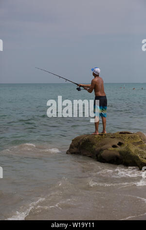 Ein junger Mann Fische aus der felsigen Atlantik Strand bei Carlin Park in Jupiter, Florida, USA. Stockfoto
