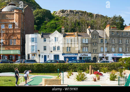 Seafront Gebäude in Hastings, East Sussex, UK, mit Minigolf Kurs im Vordergrund und West Hill im Hintergrund Stockfoto