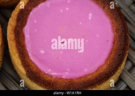 Nahaufnahme der Eigenbau niederländische Butter Kuchen (Boterkoek) Cookie mit rosa Glasur, frisch gebacken aus dem Ofen. Auf hölzernen Hintergrund angezeigt. Im Satz Stockfoto