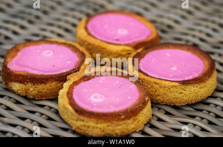 Nahaufnahme der Eigenbau niederländische Butter Kuchen (Boterkoek) Cookie mit rosa Glasur, frisch gebacken aus dem Ofen. Auf hölzernen Hintergrund angezeigt. Im Satz Stockfoto