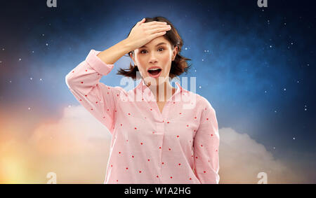 Verwirrte junge Frau im Pyjama über Nacht Himmel Stockfoto