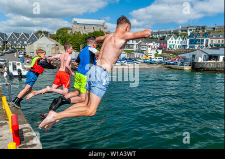 Baltimore, West Cork, Irland. 1. Juli 2019. Da die Temperaturen auf den späten Teens an einem schönen sonnigen Tag, Touristen und Einheimische nutzten die Gelegenheit, sich im Wasser abkühlen. Eine Gruppe von Jungs verbrachten den Nachmittag springen in den Hafen. Credit: Andy Gibson/Alamy Leben Nachrichten. Stockfoto