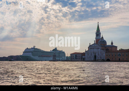 Ein riesiges Kreuzfahrtschiff in den Canale di San Marco Zwerge die Chiesa di San Giorgio Maggiore, Venedig, Italien Stockfoto