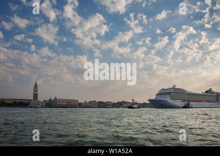 Ein riesiges Kreuzfahrtschiff in den Canale di San Marco Zwerge die Uferpromenade von San Marco, Venedig, Italien Stockfoto
