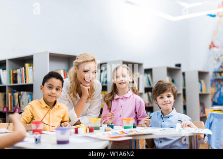 Selektiver Fokus von Happy african american Kid an der Kamera in der Nähe der lächelnde Frau und Kinder suchen Stockfoto