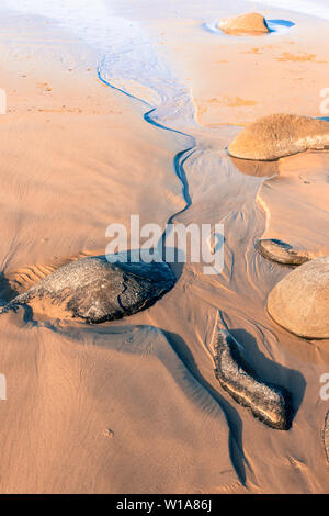 Kleiner Bach im Sand der Gezeiten Kante laufen am Strand in vertikale Komposition. Stockfoto