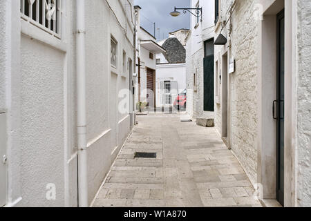 Schmale Straße mit alten Häusern auf dem Hintergrund einer Trullo Haus mit einem kegelförmigen Dach in Alberobello Stadt in Italien. Es ist ein Vintage Laterne Stockfoto