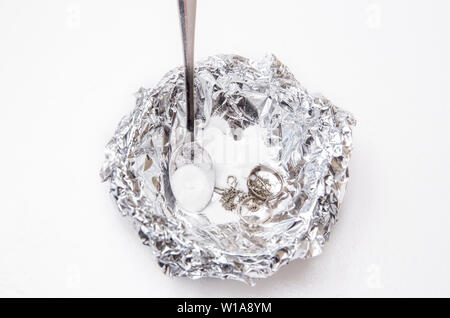 Eine Lösung aus Natron (Natriumbicarbonat) und warmem Wasser entfernen wird die Verfärbung von Silber, wenn das Silber ist in Kontakt mit einem Stück Alumini Stockfoto