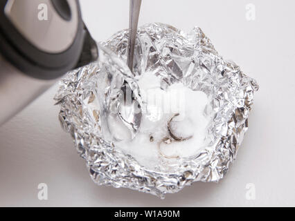 Eine Lösung aus Natron (Natriumbicarbonat) und warmem Wasser entfernen wird die Verfärbung von Silber, wenn das Silber ist in Kontakt mit einem Stück Alumini Stockfoto
